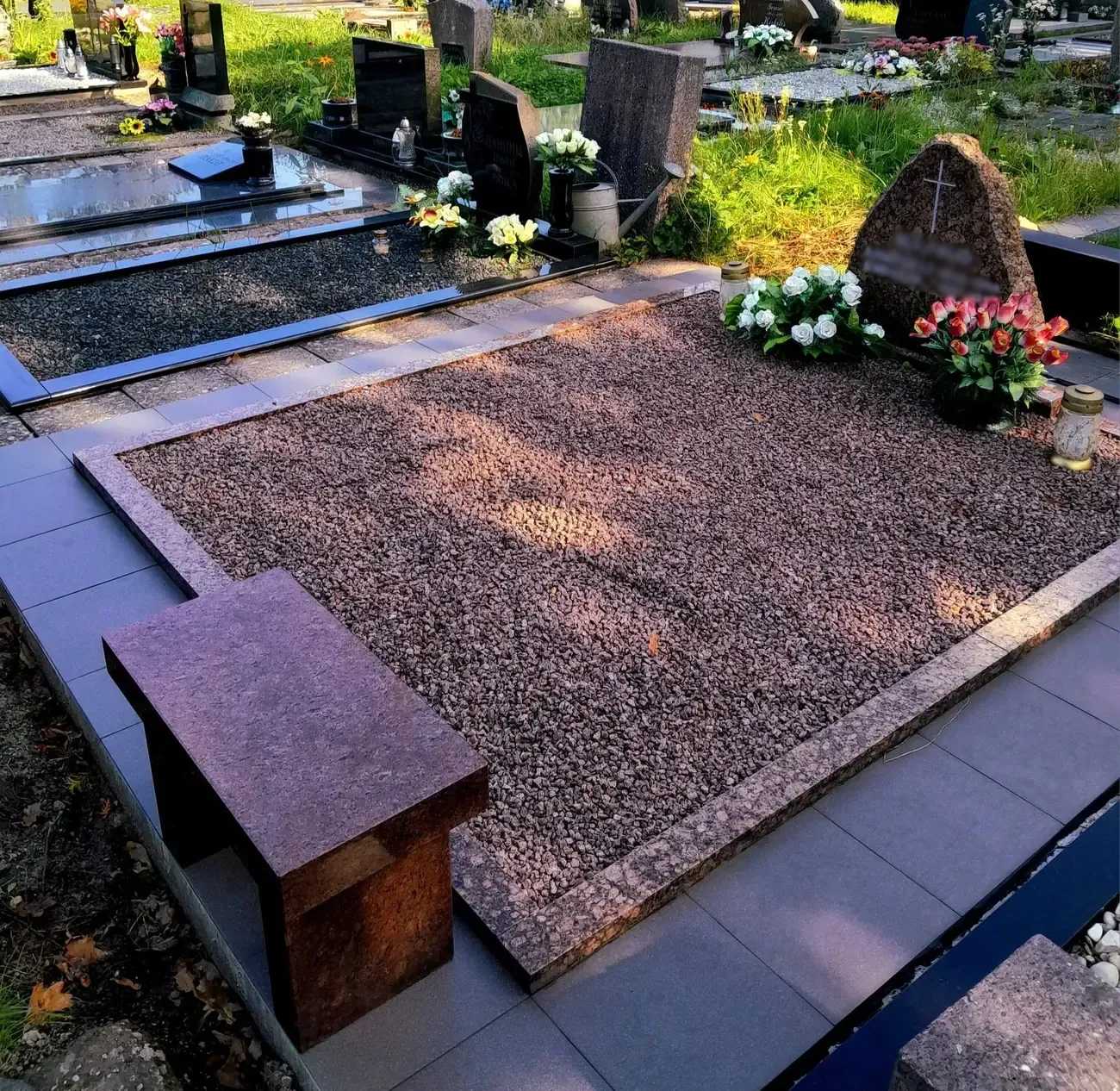 Rudo granito apvadais įrėminta kapavietė su granito skalda ir akmeniniu suoliuku